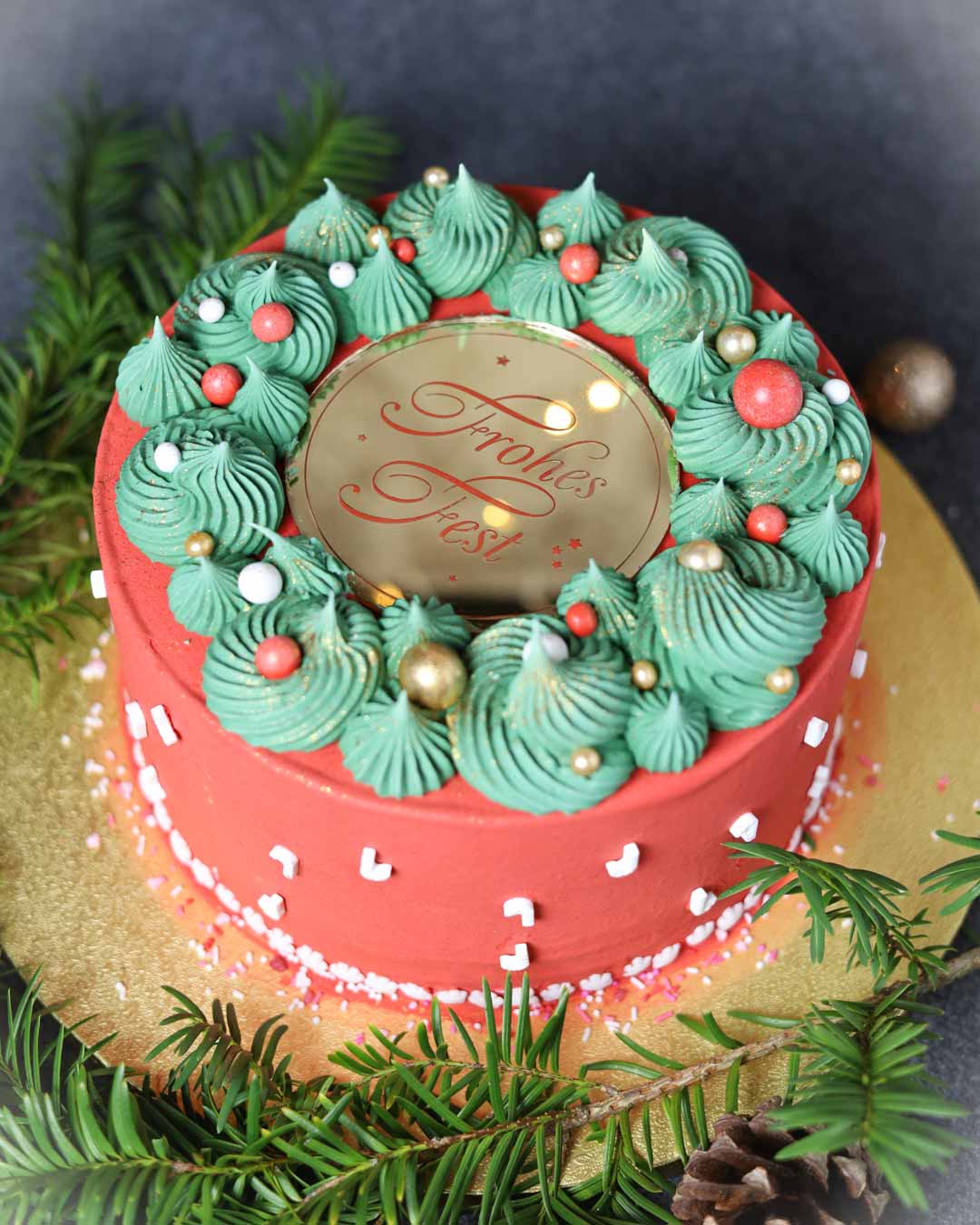 Cake Charm Frohes Fest aus Spiegelacryl Gold auf roter Weihnachtstorte mit grüner Creme und Zuckerstreuseln