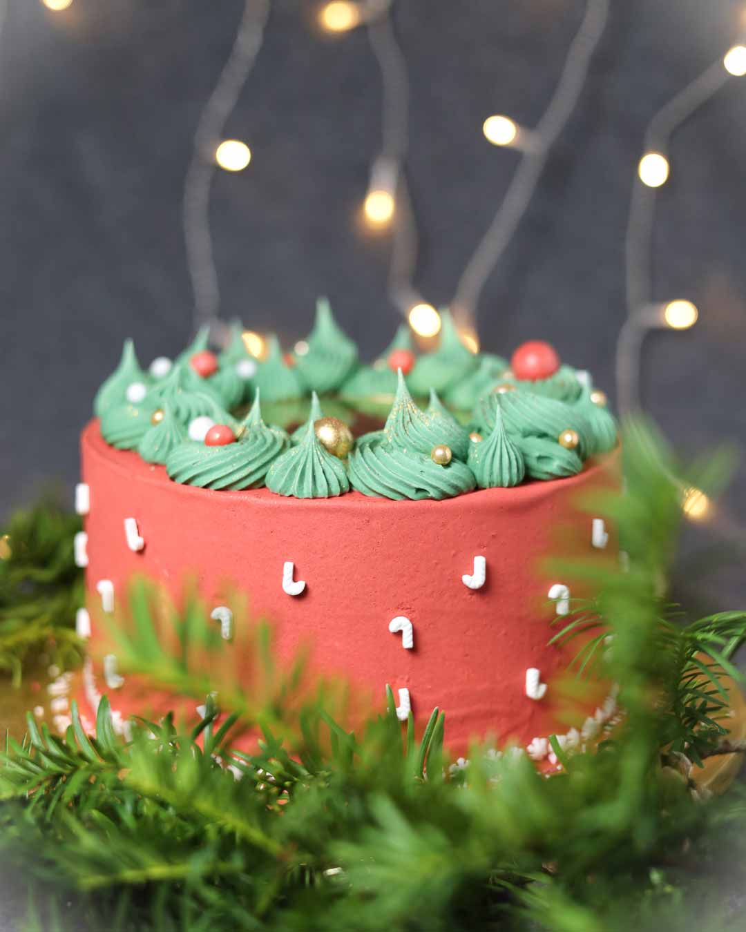 Cake Charm Frohes Fest aus Spiegelacryl Gold auf roter Weihnachtstorte mit grüner Creme und Zuckerstreuseln